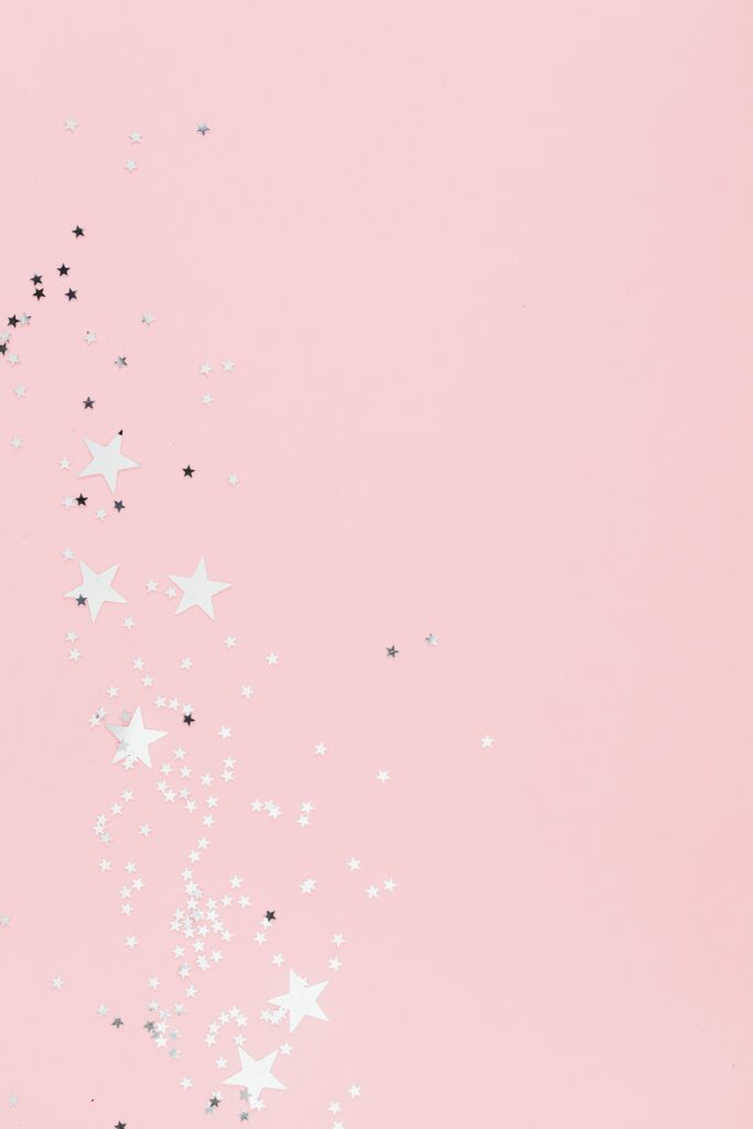 Soft pink pastel background with scattered star-shaped confetti, perfect for festive designs.